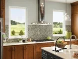 dark stained cabinets facing stove top with two casement windows on either side