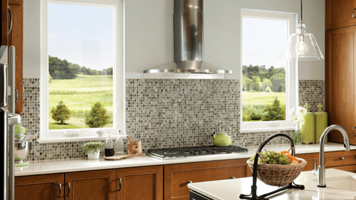 dark stained cabinets facing stove top with two casement windows on either side
