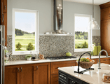 dark stained cabinets facing stove top with two casement windows on either side