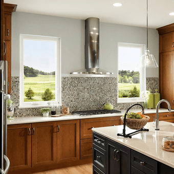 dark stained cabinets facing stove top with two casement windows on either side