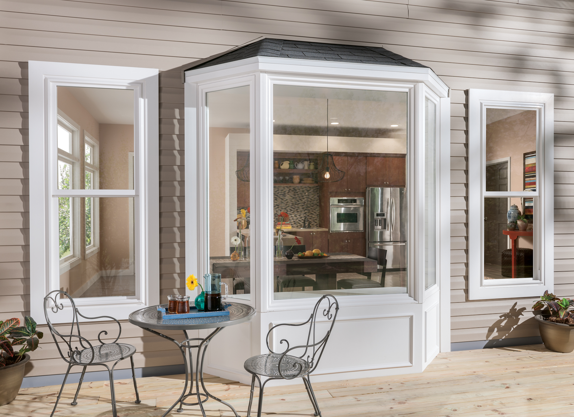 Tuscany® Series | V400 white bay windows from an exterior view with patio dining set