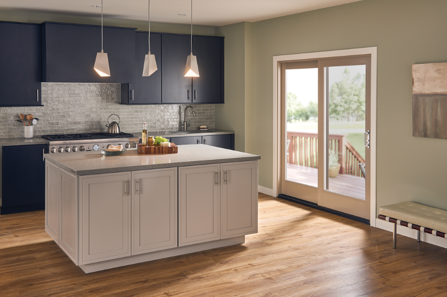 Tan Ultra Series Fiberglass sliding glass doors featured in a kitchen dark blue cabinetry and an island with tan cabinets with three pendant lights